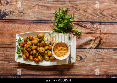 Patate fritte sfere con prezzemolo e salsa su sfondo di legno, vista dall'alto Foto Stock