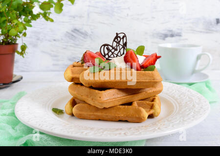 Tutto il grano cialde belghe con panna montata, tritato fresco Fragole, foglie di menta e cioccolato bianco su sfondo di legno. Le sane b Foto Stock