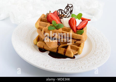 Tutto il grano cialde belghe con panna montata, tritato fresco Fragole, foglie di menta e cioccolato bianco su sfondo di legno. Le sane b Foto Stock