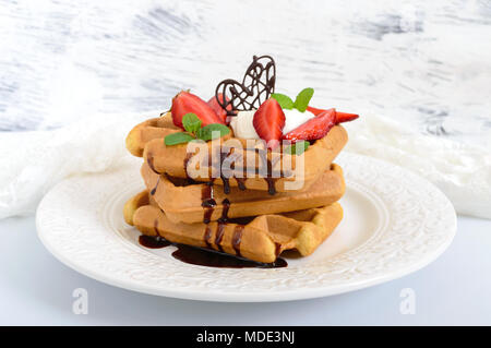 Tutto il grano cialde belghe con panna montata, tritato fresco Fragole, foglie di menta e cioccolato bianco su sfondo di legno. Le sane b Foto Stock