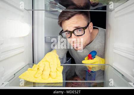 Uomo che pulisce il frigo Foto Stock