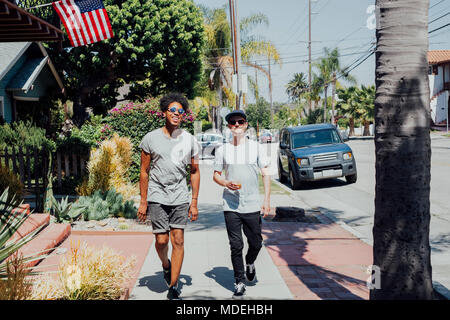 Gli amici passeggiando per le strade assolate, Long Beach, California, US Foto Stock