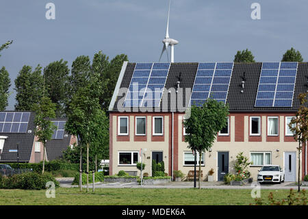 Case e rabboccato con celle fotovoltaiche con una turbina a vento dietro in Stad van de Zon (Città del Sole), un borgo sostenibile di Heerhugowaard, Olanda. Foto Stock