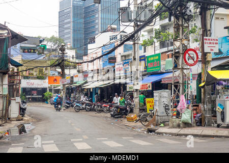 Un groviglio di linee di alimentazione aeree e ad un breve tratto di strada con moto parcheggiate e negozi nella città di Ho Chi Minh, Vietnam. Foto Stock