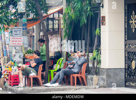 Due uomini seduti su sedie di plastica a bere un succo stradale bar nella città di Ho Chi Minh, Vietnam. Foto Stock