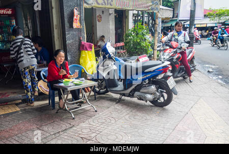 La vita quotidiana di una donna vietnamita per mangiare in un ristorante al fresco, una femmina di motociclista in Ho Chi Minh City, Vietnam. Foto Stock