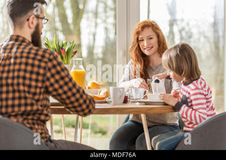 Famiglia con prima colazione insieme su una mattina di sole Foto Stock