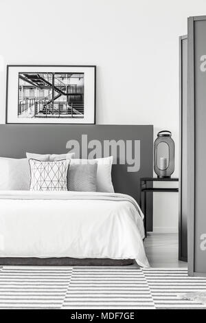 In bianco e nero poster sulla testata del letto in camera da letto semplice interno con la lanterna sul comodino Foto Stock