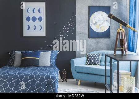 Poltrona turchese vicino al letto contro blu navy parete nella camera da letto astronomico interno con telescopio Foto Stock
