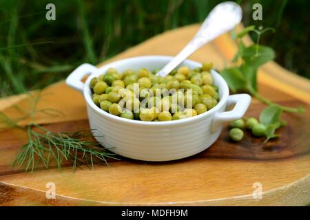 Bollito di giovani piselli verdi in una ciotola bianco. Foto Stock