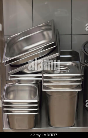 Pila di contenitori metallici in una cucina commerciale Foto Stock