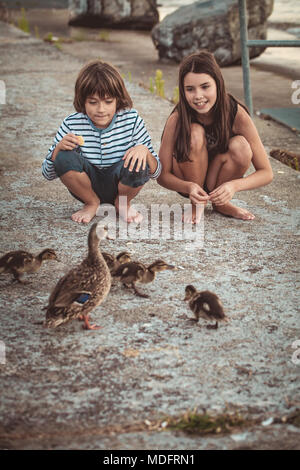 Un ragazzo e una ragazza alimentazione di anatre nel parco Foto Stock