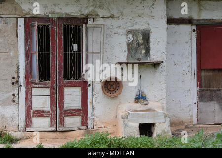 Le porte sono rosse weathered specchio e dissipatore esterno. Abbandonato il vecchio esterno della casa. Foto Stock