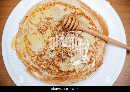 Piastra di crepes con miele e un miele drizzler Foto Stock