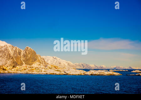 Henningsvaer, Norvegia - 09 Aprile 2018: bella vista sopra di edifici in legno con enormi mountaing dietro in Henningsvaer in Isole Lofoten Foto Stock