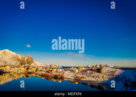 Henningsvaer, Norvegia - 09 Aprile 2018: bella vista sopra di edifici in legno con enormi mountaing dietro in Henningsvaer in Isole Lofoten Foto Stock