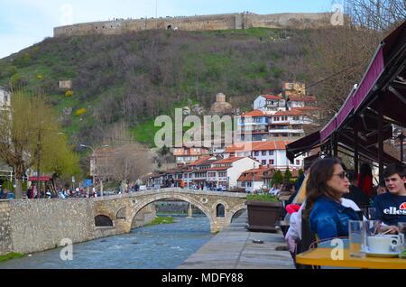 La bellissima città di Prizren nel Kosovo (ex Iugoslavia): le persone che si godono la primavera presso il fiume Bistrica. Vista del vecchio ponte in pietra e la fortezza Foto Stock