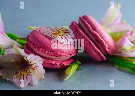 Rosa amaretto francese i cookie con alstroemeria rosa fiori su un sfondo di calcestruzzo con copia spazio. Dolcetti di San Valentino di close-up Foto Stock