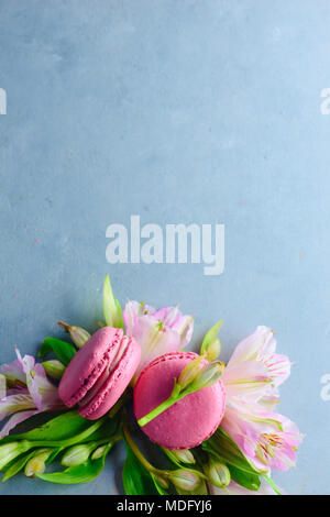 Amaretto cookies laici piatta con la primavera sbocciano i fiori su una pietra blu sfondo con copia spazio. Deserto francese di close-up. Foto Stock