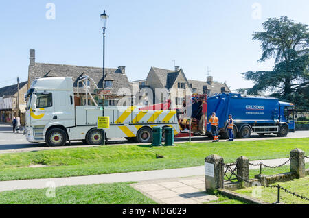 Ripartiti in camion della spazzatura o polvere carrello essendo recuperato nel famoso villaggio Costwold di Bourton-on-the-acqua, Gloucestershire in sole primaverile Foto Stock