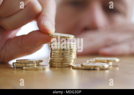 L'uomo conta monete su un tavolo. Close-up di mano mettendo una moneta alla pila di monete d'oro. Finanza aziendale e concetto di denaro Foto Stock