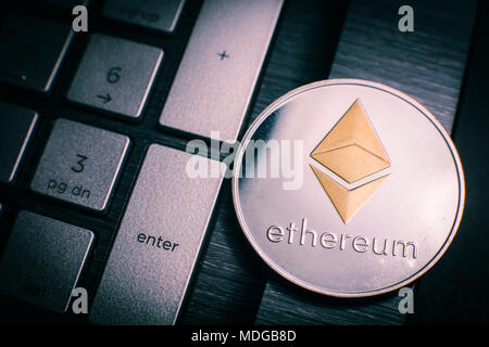Medaglia con il simbolo di Ethereum cryptocurrency posa sulla tastiera del notebook Foto Stock