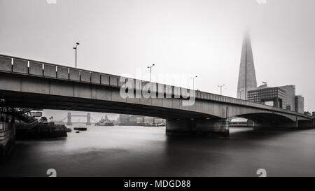 Il London Bridge e il Coccio fade dietro i foggy nebbia. Foto Stock