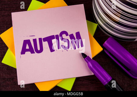 Segno di testo che mostra l'autismo. Foto concettuale di sensibilizzazione sull'Autismo condotta dal comitato sociale intorno al globo scritto una nota adesiva carta sullo sfondo di legno Foto Stock