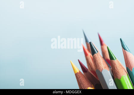 Una selezione di arte matite in diversi colori, raggruppati in basso a destra del telaio con fondo azzurro fornendo copyspace a sinistra e sopra. Foto Stock