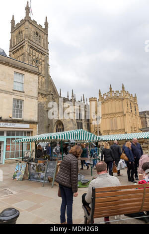 People Shopping e riposo in centro città mercato di Cirencester davanti alla Chiesa Parrocchiale di San Giovanni Battista il 07 aprile 2018 Foto Stock