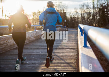 Due giovani donne in esecuzione su di un sentiero di sunrise; Anchorage in Alaska,, Stati Uniti d'America Foto Stock