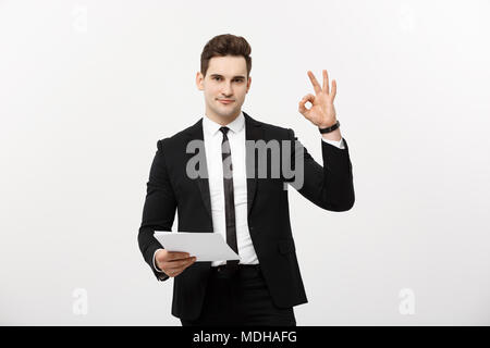 Il concetto di business: Ritratto attraente imprenditore a lavorare sulla relazione e che mostra ok dito segno. Isolate su grigio spazio copia. Foto Stock