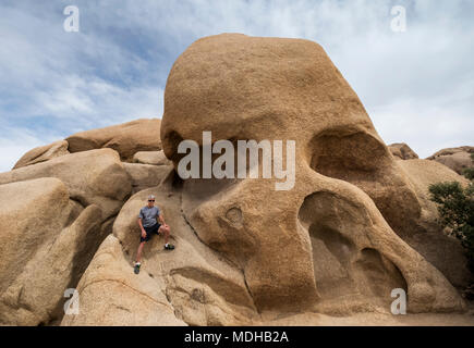 Un anziano uomo si arrampica Skull Rock a Joshua Tree National Park, California, Stati Uniti d'America Foto Stock