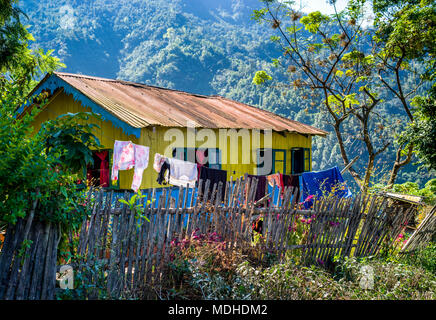 Una luminosa casa gialla con rivestimento blu e uno stendibiancheria appeso al di fuori dell'Himalaya; West Bengal, India Foto Stock