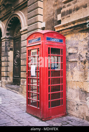 Red britannico vintage cabina telefonica al di fuori di una facciata di arenaria e costruzione di La Valletta, Malta Foto Stock