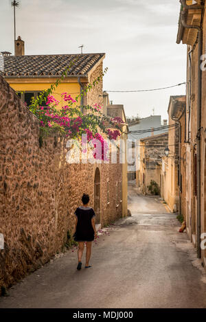 Donna che cammina giù per una strada stretta; Alcudia Maiorca, isole Baleari, Spagna Foto Stock