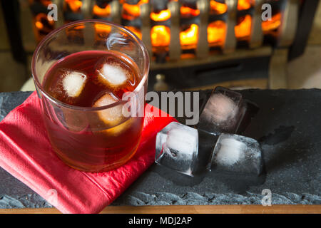 Un bicchiere di whisky sulle rocce con un background di fuoco Foto Stock