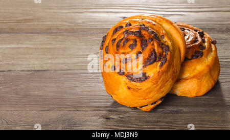 Freschi di forno bun con cioccolato su uno sfondo di legno Foto Stock