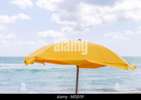 Ombrello giallo in spiaggia, uno splendido mare e l'immagine del cielo. Windy giornata estiva con onde. Miami Beach. Foto Stock