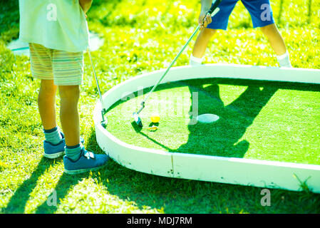 Hildren giocare sul campo da golf.Casual i bambini in un campo da golf holding club di golf. Tramonto Foto Stock