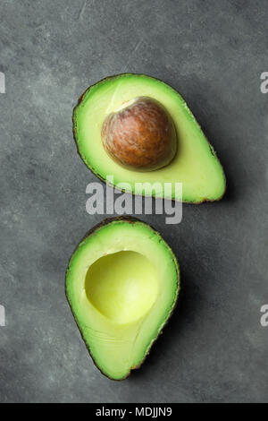 Mature bella uniformemente organico dimezzato Australian Avocado con Pit sul calcestruzzo nero lo sfondo di pietra. Uno stile di vita sano Vegan Vitamina E OLIO. Creative M Foto Stock