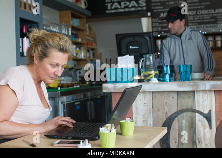 Donna al lavoro su laptop in un coffee shop Foto Stock