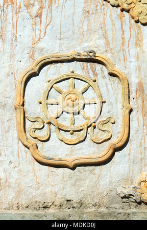 Dipinto di dharma ruota simbolo buddista, scolpito sull'entrata chorten che porta al villaggio di Ghemi, Mustang Superiore regione, Nepal. Foto Stock