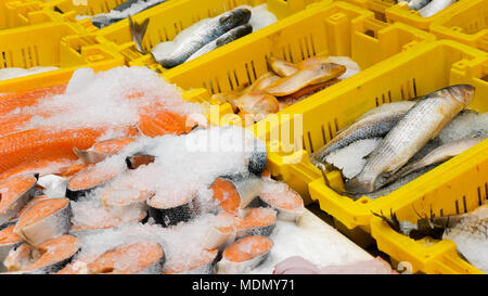Vari pesci e frutti di mare in scatole gialle presso un locale mercato Foto Stock