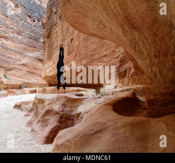 Petra Wadi Musa, Giordania, 9 Marzo 2018: un giovane turista in un nero tuta sportiva praticando un handstand al Siq nel deserto Foto Stock