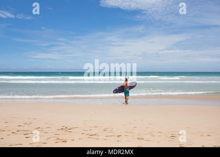 Mirissa/Sri Lanka - Aprile 9, 2018: Maschio surfer camminando lungo la riva con una tavola da surf. Foto Stock