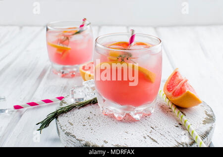 Cocktail con fette di pompelmo e ghiaccio, gli ingredienti per un drink su bianco tavolo in legno, spazio di copia Foto Stock
