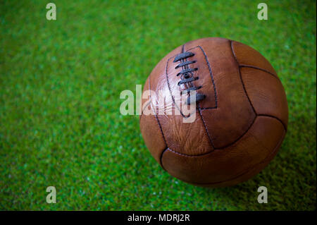 Vista ravvicinata di un vintage, in pelle marrone (circa 1930) calcio sul verde lussureggiante sfondo di erba Foto Stock