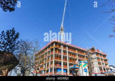Guscio di un nuovo appartamento residenziale blocco in costruzione vicino alla stazione ferroviaria e la torre bianca gru, Woking, Surrey, Regno Unito in una giornata di sole Foto Stock