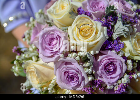 Anelli in un viola e bianco bouquet della sposa Foto Stock